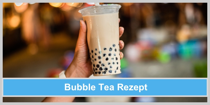 Bubble Tea Rezept: Eine Hand hält einen milchigen Bubble Tea mit schwarzen Perlen in einem durchsichtigen Becher in die Luft.