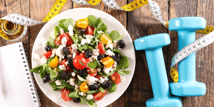 Ein Teller mit Salat, Kurzhanteln und Maßband Wie du Ernährung, Bewegung und Alltag in Einklang bringst